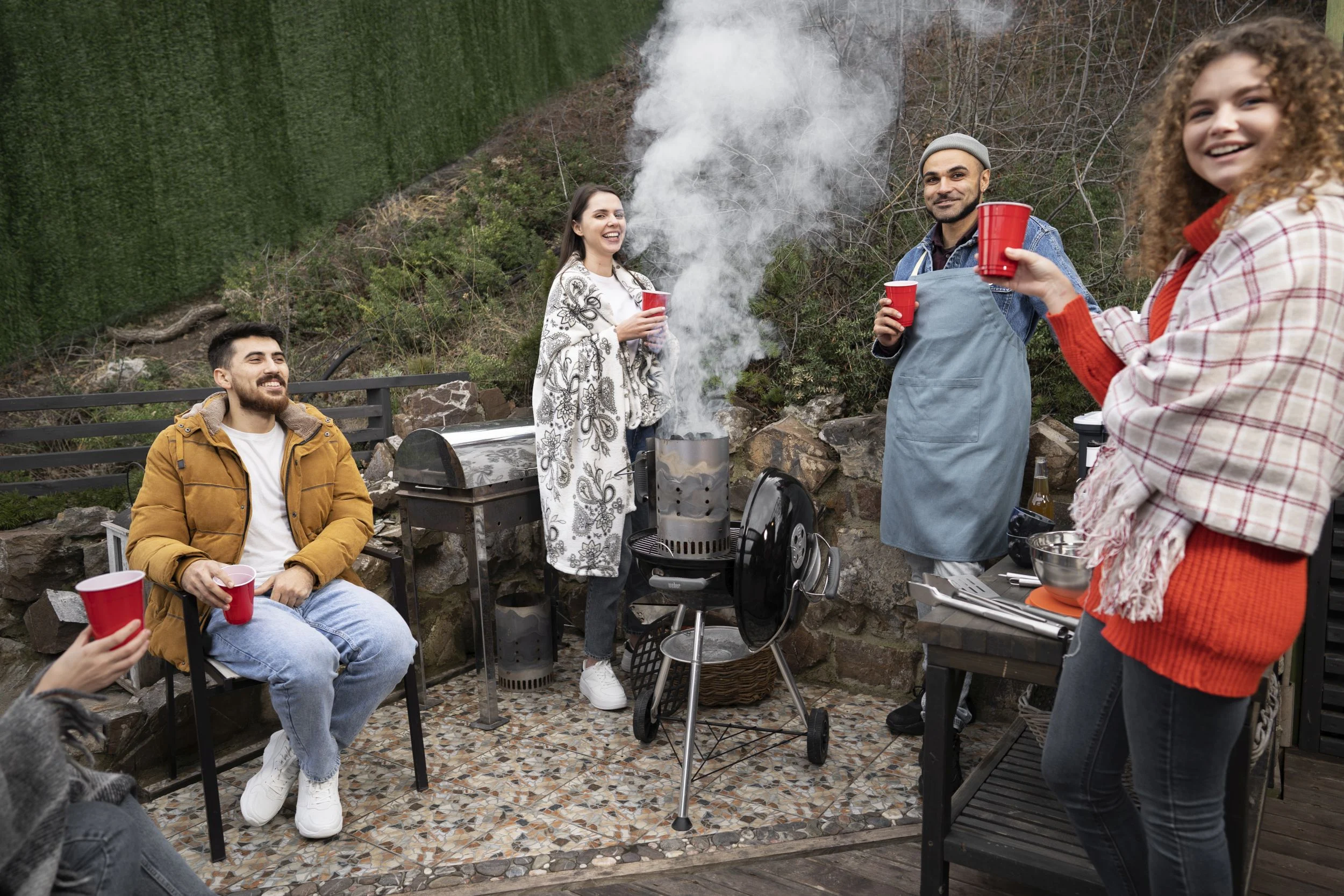 Person preparing food on a folding barbecue while camping outdoors