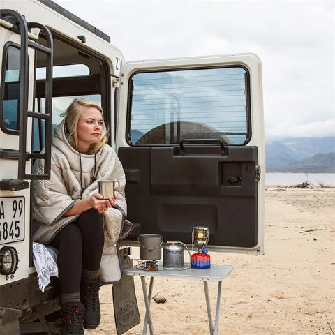 A person sleeping comfortably in a tent while camping, emphasizing warmth and proper attire.